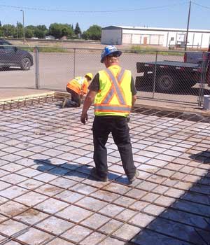 two construction workers leveling the cement blocks laid on the flooring